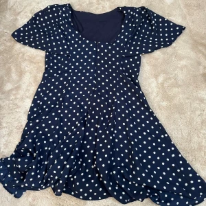 Mörkblå prickig klänning från Zara - Säljer en superfin mörkblå klänning från Zara med vita prickar. Den har korta ärmar och en söt, fladdrig passform som är perfekt för sommardagar. Klänningen är i nyskick och redo för nya äventyr! 🌟