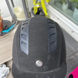 Ridhjälm - Den är väl använd men ändå i bra skick. Den har varit med om väder, vind och fall från hästryggen. Den har glittriga sträck på sidan och luftintag.