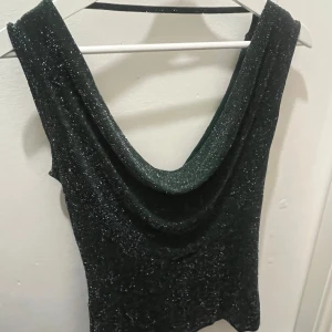 Grön glittrig topp - Jättesöt grön och glittrig topp med djup urringning fram och bak. Är jättefin att ha både fram och baklänges och passar perfekt till fest. 🫶