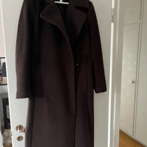 Brun kappa från H&M - Säljer en snygg brun kappa från H&M i storlek 36. Den är perfekt för höst och vinter med sin stilrena design och långa ärmar. Kappan har en klassisk krage och är gjord i ett mjukt material. knappt använd, är till knäna på mig som är 175cm.