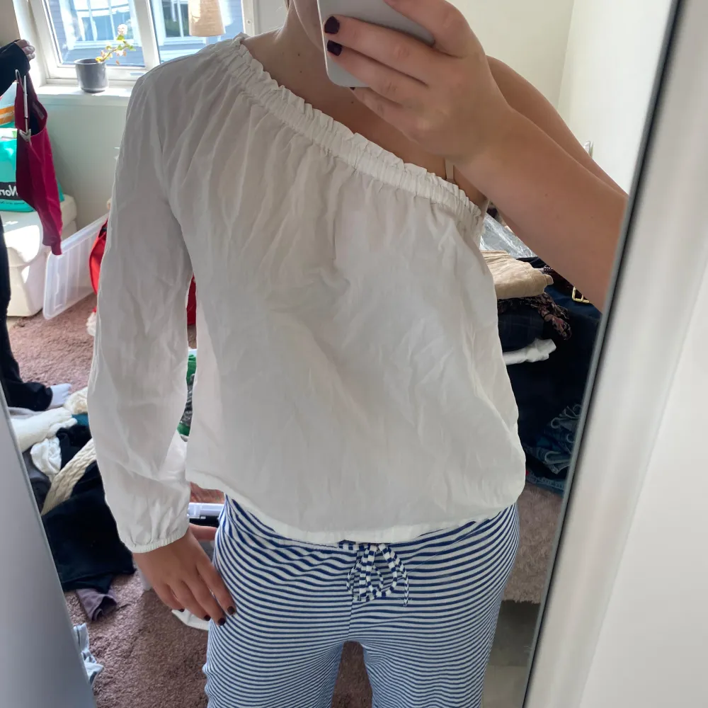 Säljer en snygg vit oneshoulder topp med lång ärm. Perfekt för en stilren och chic look. Toppen är i ett lätt och bekvämt material, perfekt för både vardag och fest.. Toppar.