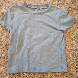 Ljusblå t-shirt från H&M - Säljer en enkel och stilren ljusblå t-shirt från H&M. Bra skick.