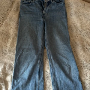 Blå jeans från Weekday - Säljer ett par snygga blå jeans från Weekday i modellen Rowe. De är i en klassisk straight fit och har en hög midja. Perfekta för både vardag och fest! Jeansen är i bra skick och har en tidlös design med fem fickor och knappgylf.