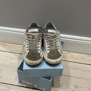 Sneakers från Philippe Model - Snygga sneakers från Philippe Model i beige/grå med blå detaljer. Skorna har en klassisk snörning och är tillverkade i mocka och syntetmaterial. Perfekta för en avslappnad stil.