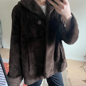 Brun pälsjacka - Säljer en mysig brun pälsjacka med stora knappar framtill. Jackan har en lös passform och långa ärmar,  Perfekt för att hålla sig varm och stilren. Jackan har en ficka som inte är fastsydd (de sista bilden) 