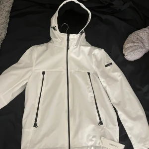 Vit jacka från Calvin Klein - Säljer en helt oanvänd stilren vit jacka från Calvin Klein med svart foder som har kvar prislapp. Jackan har en huva och dragkedja framtill samt två praktiska fickor med dragkedjor, INGA defekter (fläckar, traskigt osv). Perfekt för kyligare dagar. Nypris: 3000kr pris KAN diskuteras vid SNABB affär! (för fler bilder hör av er!)