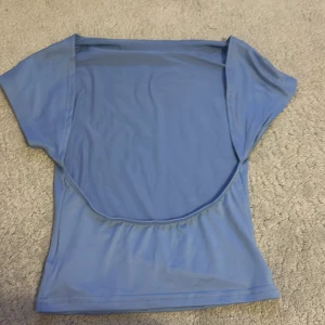 Blå topp öppen rygg från Shein - Säljer en ljusblå topp från Shein. Toppen har korta ärmar och en enkel design, perfekt för en avslappnad stil. Tillverkad i ett mjukt och bekvämt material.