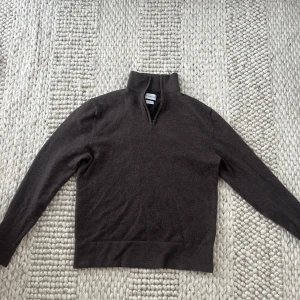 Brun merinoulltröja med zip från These Glory Days - Säljer en stilren brun tröja i merinoull från These Glory Days. Tröjan har en dragkedja vid halsen och långa ärmar, otroligt snygg som övertröja! Använd fåtal gånger så det är som ny!! 