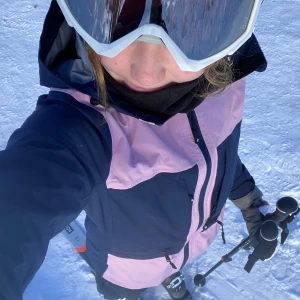 Blå och rosa jacka med huva - Säljer en snygg blå/rosa skidjacka med huva. Jackan har dragkedja framtill samt dragkedja i armhålan och flera praktiska fickor, samt liftkortsficka på vänstra armen. Den är stl S och luvan rymmer en hjälm