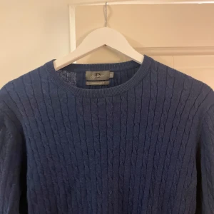 Marin blå Kashmir tröja - Säljer en elegant mörkblå tröja från Signature i kashmirblandning. Tröjan har ett stilrent kabelstickat mönster och långa ärmar med ribbade muddar. Perfekt för kyligare dagar.