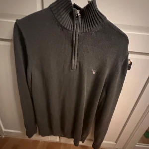 Grå tröja med dragkedja från Gant - Säljer en stilren grå tröja från Gant med dragkedja och hög krage. Perfekt för kyligare dagar. Tröjan har långa ärmar och en liten logga på bröstet. Passar både till vardags och mer uppklädda tillfällen. Den e som ny, säljer för intr min stil, pris kan diskuteras 
