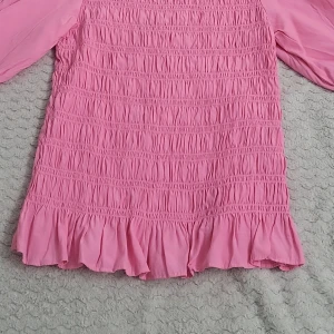 Rosa blus med volangdetaljer - Säljer en söt rosa blus med volangdetaljer och trekvartsärmar. Blusen har en smockad design som ger en fin passform och en feminin touch. Perfekt för att liva upp garderoben!