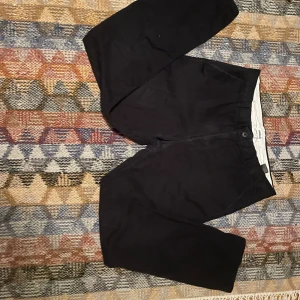 Svarta byxor från Weekday - Snygga svarta byxor från Weekday med en klassisk design. De har en rak passform och är perfekta för en stilren look. Byxorna har en dragkedja och knapp framtill.