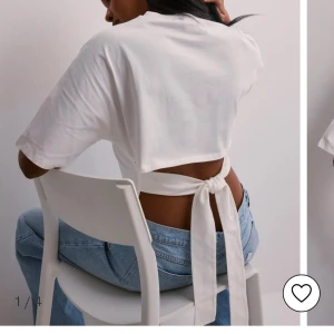 Vit kortärmad topp med knyt - Säljer en stilren vit topp med korta ärmar och en unik knytning i ryggen. Perfekt för en avslappnad och trendig look. Passar bra till jeans eller kjol.
