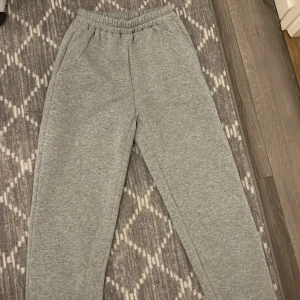 Grå mjukisbyxor - Säljer ett par bekväma grå mjukisbyxor med elastisk midja och muddar vid bensluten. Perfekta för en avslappnad dag hemma eller en promenad i parken. Byxorna har praktiska sidofickor för småsaker.