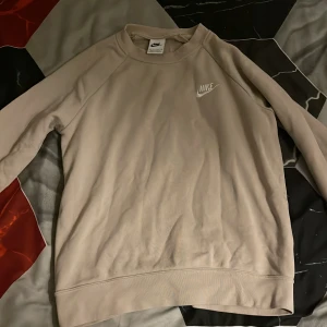 Beige tröja från Nike - Säljer en stilren beige tröja från Nike med deras klassiska logga på bröstet. Tröjan har långa ärmar och en bekväm passform. Perfekt för en avslappnad look.storlek XS helt ny inte alls använd fick fel storlek 