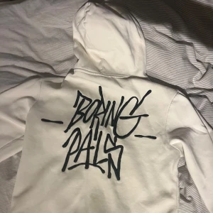 Vit hoodie med tryck från H&M - Säljer en vit hoodie från H&M. Den är i bra skick och texten på tröjan är med tråd och inte tryckt! 