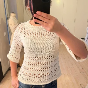 Vit stickad trekvartsärmad topp - Säljer en vit stickad topp från Three Sixty Five med trekvartsärm och ett snyggt hålmönster. Perfekt för vår och sommar. Toppen har en rund halsringning och är både stilren och bekväm.