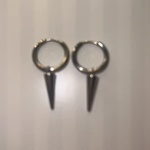 Silvriga örhängen med konformad detalj - Snygga silvriga örhängen med en unik konformad hängande detalj. Perfekta för att ge en edgy touch till din stil. Passar både till vardag och speciella tillfällen.