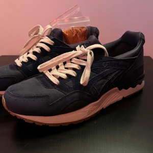 ASICS Gel-Lyte V Peacoat Sneakers - Snygga ASICS Gel-Lyte V sneakers i färgen Peacoat. Skorna har en mörkblå nyans med ljusa snören och en bekväm gummisula. Perfekta för en stilren och sportig look.