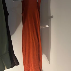 Orange ärmlös klänning - Snygg orange ärmlös klänning med v-ringad design. Perfekt för varma dagar med sin lätta och bekväma passform.