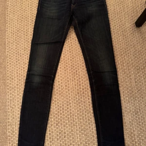 Mörkblå jeans från Replay - Snygga mörkblå jeans från Replay med en tight passform. Skönt slitna. Klassisk design med fem fickor och knappgylf. Perfekta för en stilren look.