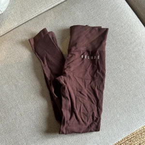 Bruna leggings från Relode SLIPSTREAM  - Snygga bruna leggings från Relode med hög midja och ribbade detaljer. Perfekta för träning eller en avslappnad dag. Materialet är stretchigt och bekvämt. 