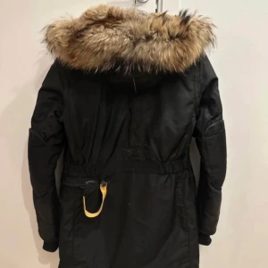 Svart parkajacka från Parajumpers - Säljer en svart parkajacka från Parajumpers med en mysig pälsfodrad huva. Jackan har flera praktiska fickor och en dragkedja framtill. Perfekt för kalla vinterdagar.