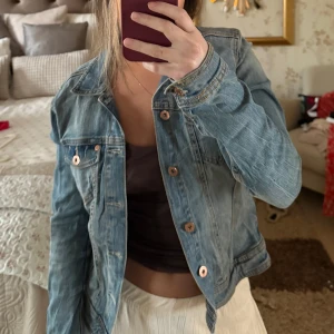 Blå jeansjacka från H&M - Säljer en klassisk blå jeansjacka från H&M med knappar framtill och två bröstfickor. Jackan har en normal passform och är perfekt för vår❤️