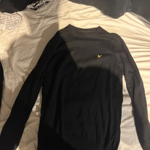 Svart långärmad tröja från Lyle & Scott - Säljer en stilren svart långärmad tröja från Lyle & Scott med deras ikoniska gula logga på bröstet. Perfekt för en avslappnad men ändå snygg look. Tröjan är gjord i ett mjukt material som känns skönt mot huden. Skick 10/10 aldrig använd och det är derför jag säljer den pris kan diskuteras vid snabb affär 