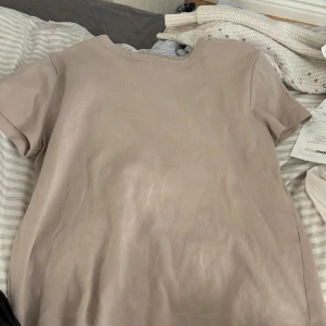 Beige t-shirt från Zara - Säljer en stilren beige t-shirt från Zara. Den har en normal passform och är kortärmad, perfekt för en avslappnad look. Tillverkad i ett mjukt material som känns skönt mot huden.