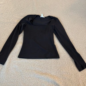 Svart långärmad topp - Snygg svart långärmad topp med en elegant och enkel design. Perfekt för både vardag och speciella tillfällen. Den har en rundad hals och är tillverkad i ett mjukt material för extra komfort.
