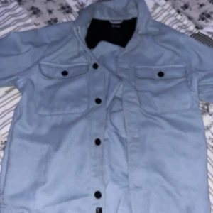 Ljusblå overshirt från Only & Sons - Säljer en ljusblå overshirt från Only & Sons. Jackan har knappar framtill och två bröstfickor med lock. Perfekt för lager-på-lager-stil.
