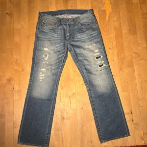 True Religion - Snygga blåa trueys med slitningar och broderade detaljer. De har storleken W38 samt passformen straight. Nypris ca 2700kr. Knappt använda då de ej passar mig. Kom med bud!