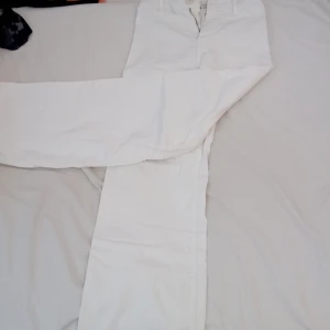 Vita jeans från Zara - Säljer ett par vita jeans från Zara i storlek 164. Byxorna har en klassisk design med knapp och dragkedja framtill. De är raka i modellen och har fransade kanter vid bensluten för en trendig look.