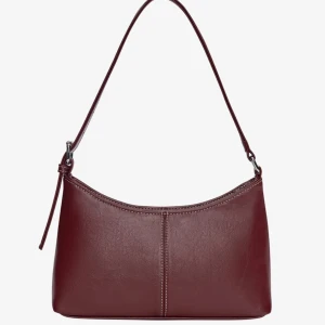 Vinröd axelväska - Vinröd/ burgundy axelväska i syntetmaterial. Använd två gånger. Perfekt för att bära dina dagliga nödvändigheter med stil.