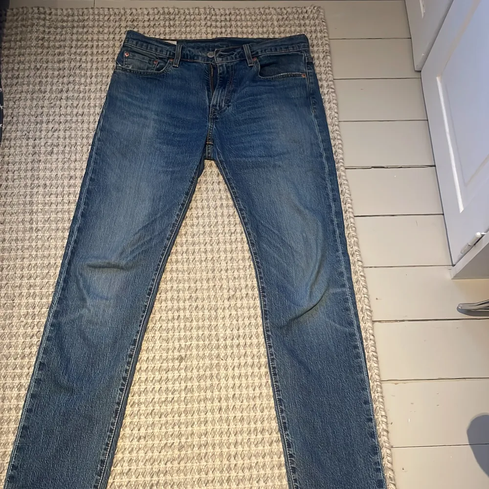 Säljer ett par klassiska Levi's 502 jeans i blå denim. De har en straight passform och är perfekta för en avslappnad stil. Jeansen har fem fickor och en dragkedja med knappstängning.. Farkut & Housut.