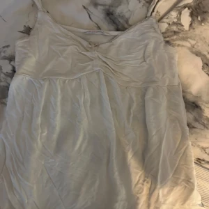 Vitt linne från odd Molly - Söt vitt linne som ej säljs längre på deras hemsida med smala axelband och en liten broderad detalj i rött på baksidan. Linnet har en v-ringad design framtill och är gjord i ett lätt och luftigt material, perfekt för varma dagar.☺️