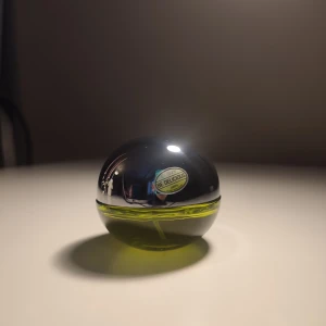 Parfym Be Delicious från DKNY - Säljer en fräsch parfym från DKNY, Be Delicious, med en unik äppelformad flaska. Flaskan är i en kombination av silver och genomskinligt grönt glas, vilket ger en modern och stilren look. 30 ml. Perfekt för den som älskar fruktiga och fräscha dofter. Parfymen är knappt använd, endast testas.