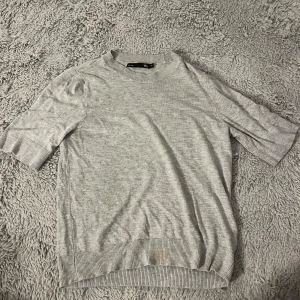 Grå stickad tröja från 157 - Säljer en stilren grå tröja från 157 i storlek XS. Tröjan har korta ärmar och en rund halsringning med ribbade kanter och är stickad. Extremt skön