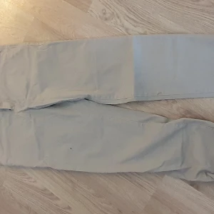 Beige chinos slim fit byxor från Orgnls - Snygga beige slim fit byxor från Orgnls. Chinos byxorna har en klassisk design med dragkedja och knapp framtill. Perfekta för en stilren look.