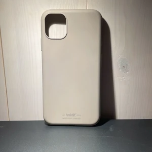 Beige mobilskal från Holdit - Snyggt och stilrent beige mobilskal från Holdit. Skalet är designat för att skydda din telefon och har en slät yta med exakta utskärningar för knappar och kamera. Perfekt för att ge din mobil ett minimalistiskt utseende.