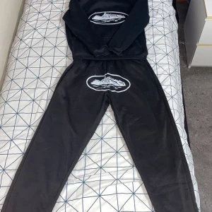 Corteiz  - Säljer dn svart hoodie och svarta byxor med ett stort vitt tryck på framsidan. Tröjan har en klassisk huva och långa ärmar, perfekt för en avslappnad stil och byxorna är jättesköna och bra material. Aldrig använda, helt nya. Vill sälja de pågrund av att de är små för mig. Kan tänka mig gå ner i pris vid snabb affär. Hör av dig vid minsta fundering:)