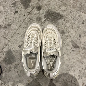 Vita Nike sneakers - Säljer ett par vita Nike sneakers med snygg design och bekväm passform. Skorna har snörning och en stilren look som passar perfekt till vardags. 