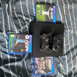 PlayStation 4 med spel och kontroller - Säljer en PlayStation 4 med två svarta kontroller och tre spel: EA Sports FC 24, EA Sports FC 25 och Call of Duty WWII. Perfekt för spelkvällar med vänner eller familj. Allt är i bra skick och fungerar utmärkt. Kontakta mig för mer information eller om du är intresserad av att köpa.