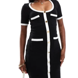 Tweedklänning med guldknappar, kontrastkanter - Elegant svart långklänning med vita kanter och knappar framtill. Klänningen har korta ärmar och en figurnära passform. Perfekt för en stilren look. Insydd