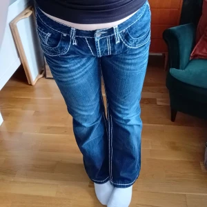 Blå contastitch jeans - Snygga blå bootcut jeans med vita sömmar och låg midja. Påminner mig om True Religion. Köpte på en second hand marknad i italien. Vintage, från ett märke som heter Camp David. Jeansstorlek W32. 100 % bomull🩷