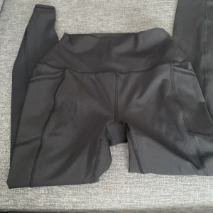 Svarta leggings från RBX - Säljer ett par svarta leggings från RBX i storlek S. De är tillverkade av 75% polyester och 25% spandex, vilket gör dem superstretchiga och bekväma. Perfekta för träning eller en avslappnad dag. De har en hög midja och en tight passform som ger bra stöd.