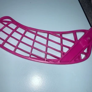 Rosa innebandyblad från Unihoc - Säljer ett rosa innebandyblad från Unihoc. Bladet är i plast och har en snygg, modern design med ett rutnätmönster. Perfekt för innebandyspelare som vill ha en färgglad och pålitlig utrustning. Passar de flesta innebandyklubbor.