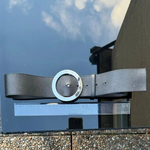 Svart skärp med rund silverfärgad spänne - NYTT Svart skärp med ett stort rundt silverfärgad spänne. Ca 88,5 cm långt. Skärpet är nytt. Det är justerbart med flera hål för att passa olika storlekar.  72 cm till innersta hålet. 79 till sista. Ca 5cm brett. Hämtas på Hägerstensåsen eller ök 🖤